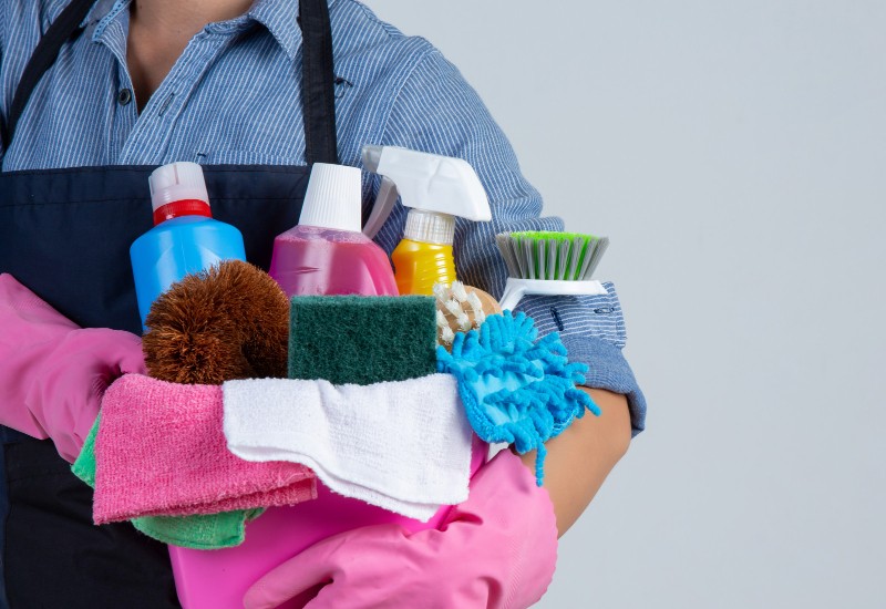 a housekeeper is holding a bucket of cleaning products